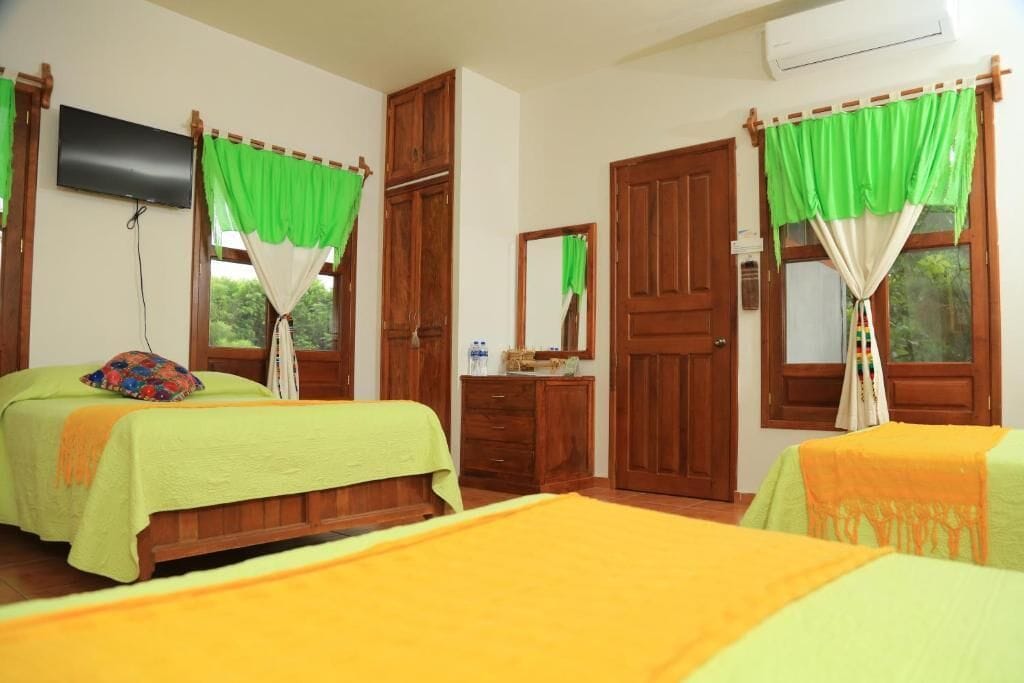 A room with two beds, a wooden wardrobe, a mirror, and a television on the wall.