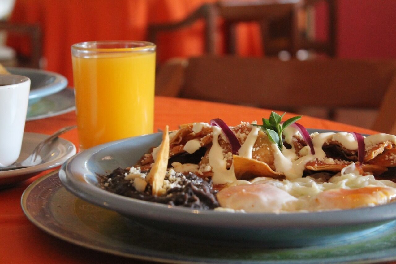 A plate of food with a glass of orange juice on a table.