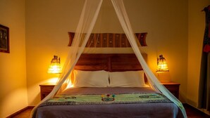 Cama com dossel, duas luminárias de cabeceira e cabeceira decorativa.