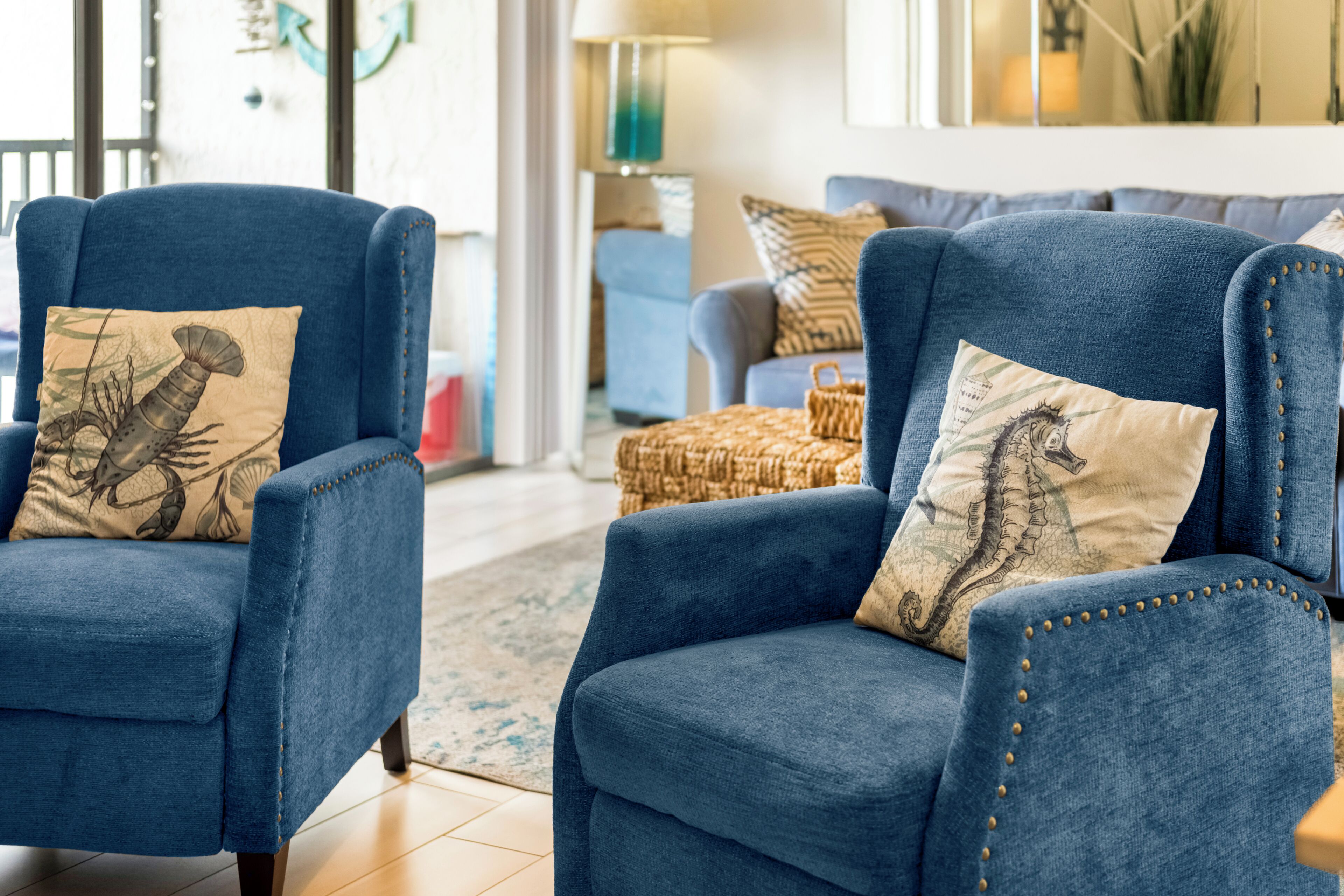Een woonkamer met twee blauwe fauteuils, elk voorzien van een decoratief kussen.