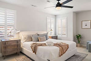 A bedroom with a bed, nightstands, a ceiling fan, and a window with blinds.