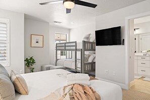A bedroom with bunk beds, a bedside table, a plant, and a window with a view.