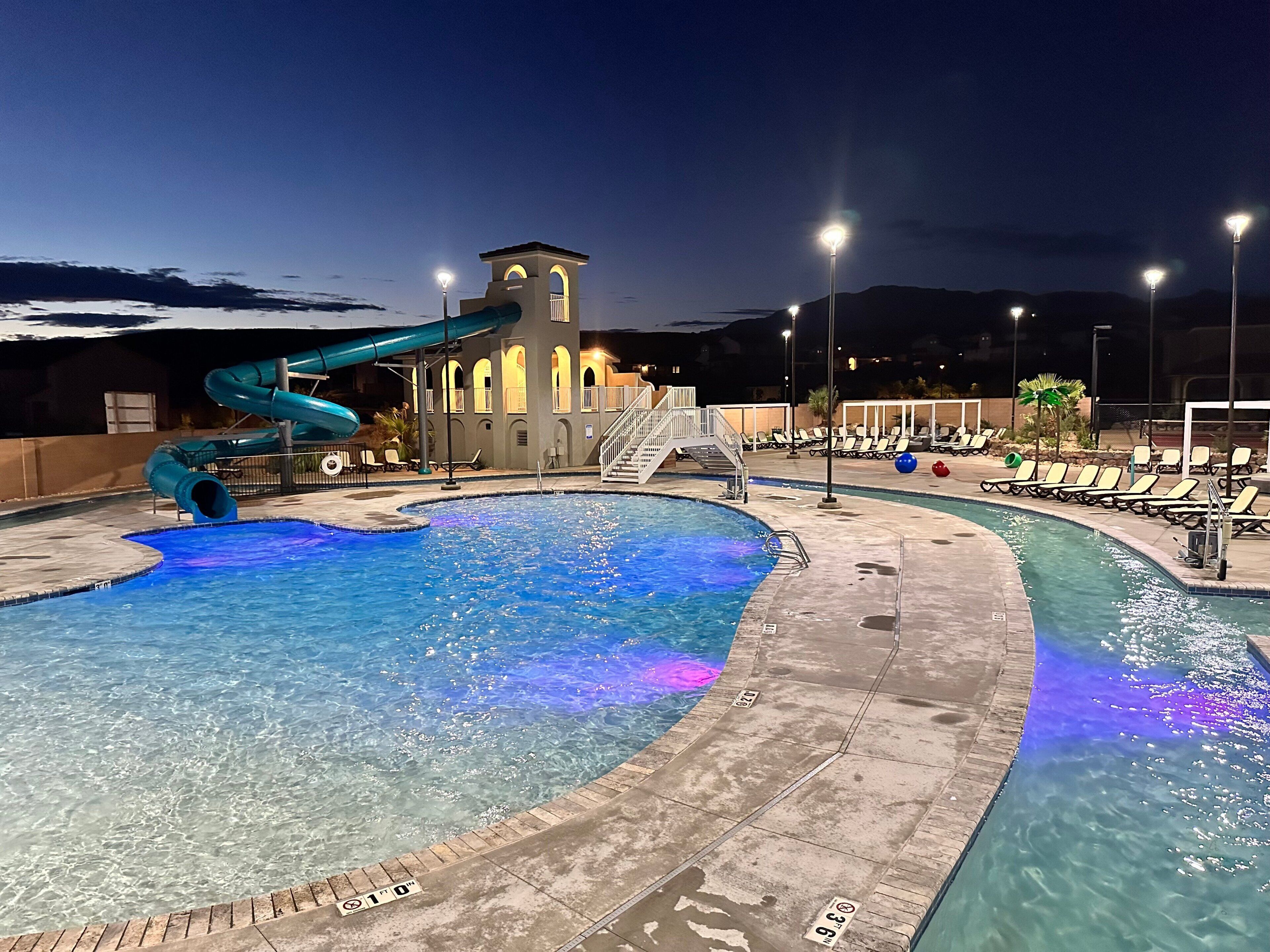 A swimming pool with a water slide and a tower structure in the background.