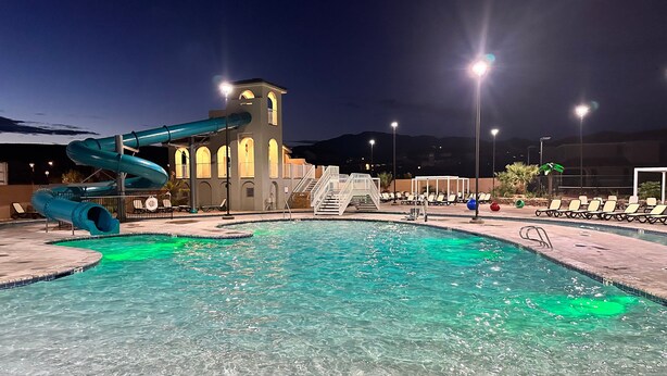 Una piscina con tobogán de agua, una torre y sillas de descanso.