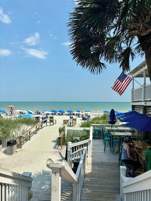 A beachside restaurant with outdoor seating overlooking the ocean, a wooden deck, and a view of the beach. - Tupelo Bay Getaway. Stylish & Upscale Villa. Newly Built. Beach,Golf,Pools,Sun! (Murrells Inlet)