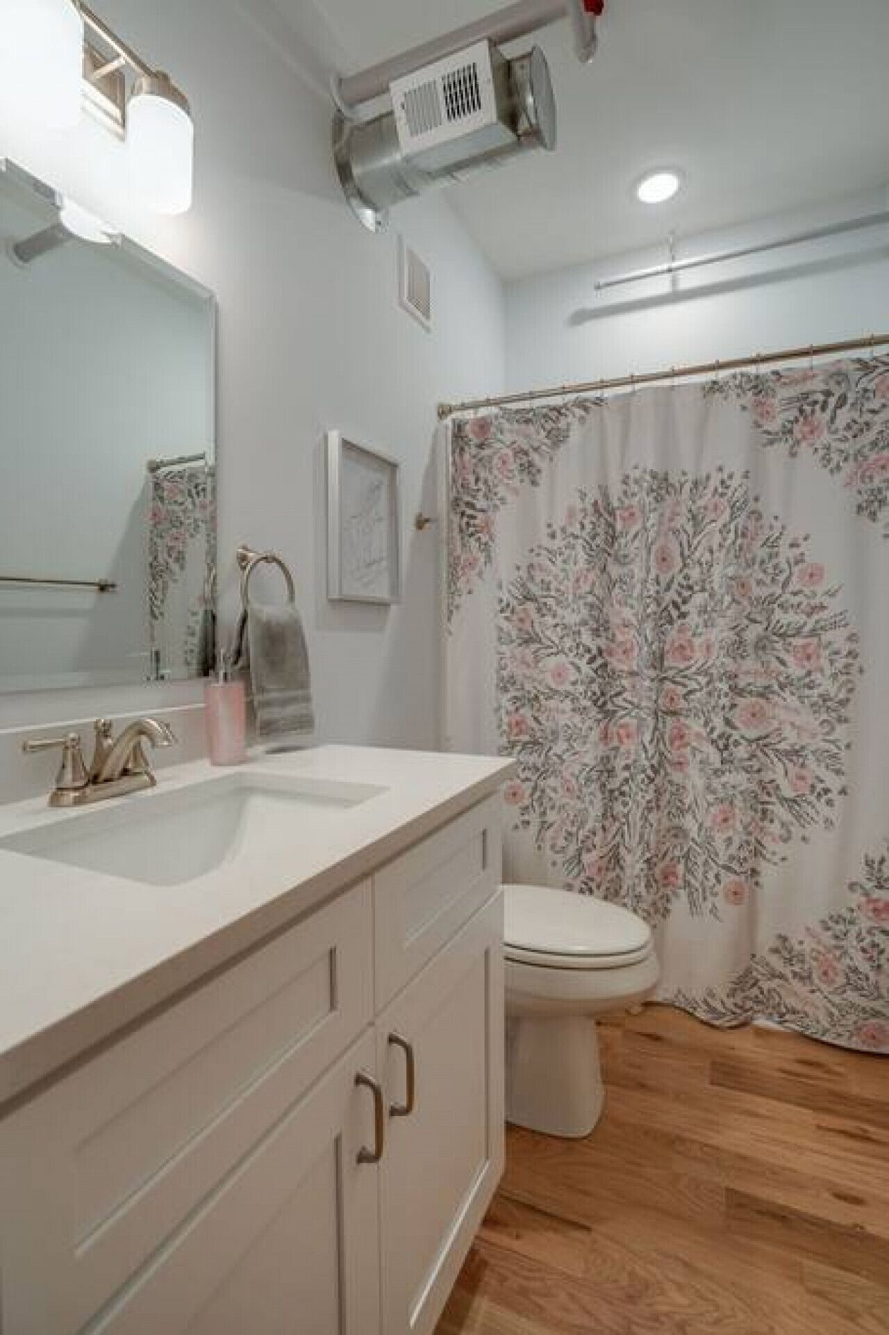 A bathroom with a white sink, a toilet, and a shower curtain with a floral pattern.