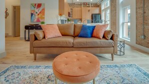 A modern living room with a sofa, ottoman, and a colorful rug. - Majestic Lofts #201- Printers Alley Area (Nashville)