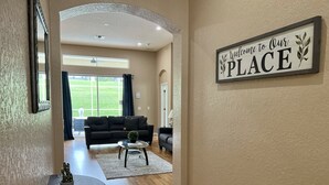 En stue med en sort sofa, et sofabord og et skilt der står "Welcome to Our PLACE".