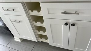 Una cocina con armarios blancos, encimera de mármol y suelo de baldosas.