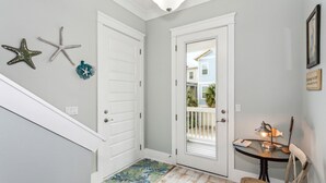 A hallway with a white door, a small table with a lamp, and starfish decorations on the wall. - Seaside Cottage: Community Pool, Hot Tub and Gated. Sleeps 11. Dog Friendly! (Navarre)