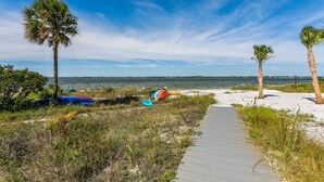 A beach path with palm trees, a sandy area, and a view of the ocean. - Seaside Cottage: Community Pool, Hot Tub and Gated. Sleeps 11. Dog Friendly! (Navarre)