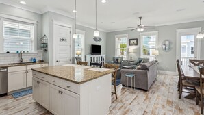 A spacious kitchen with granite countertops, a dining area with a gray sofa, and a ceiling fan. - Seaside Cottage: Community Pool, Hot Tub and Gated. Sleeps 11. Dog Friendly! (Navarre)