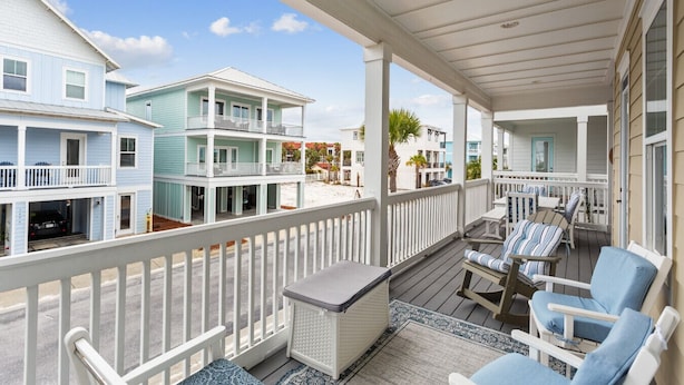 A beachfront property with a covered porch, outdoor seating, and multiple balconies. - Seaside Cottage: Community Pool, Hot Tub and Gated. Sleeps 11. Dog Friendly! (Navarre)