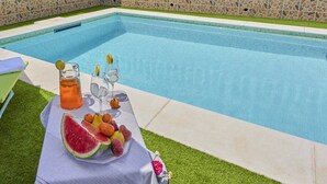Een tafel bij het zwembad met een fruitschaal, een karaf en glazen.