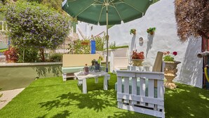 Een terras met een tafel, stoelen en een groene parasol.