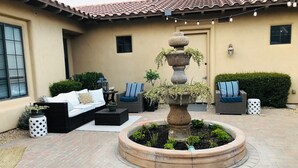 A courtyard with a stone fountain, outdoor seating, and a tiled roof. - Private Casita w/ New Full Kitchen, Private Pool, Gated Community (Goodyear)