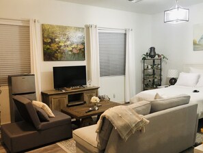A modern living room with a sofa, a television, a coffee table, and a bookshelf.