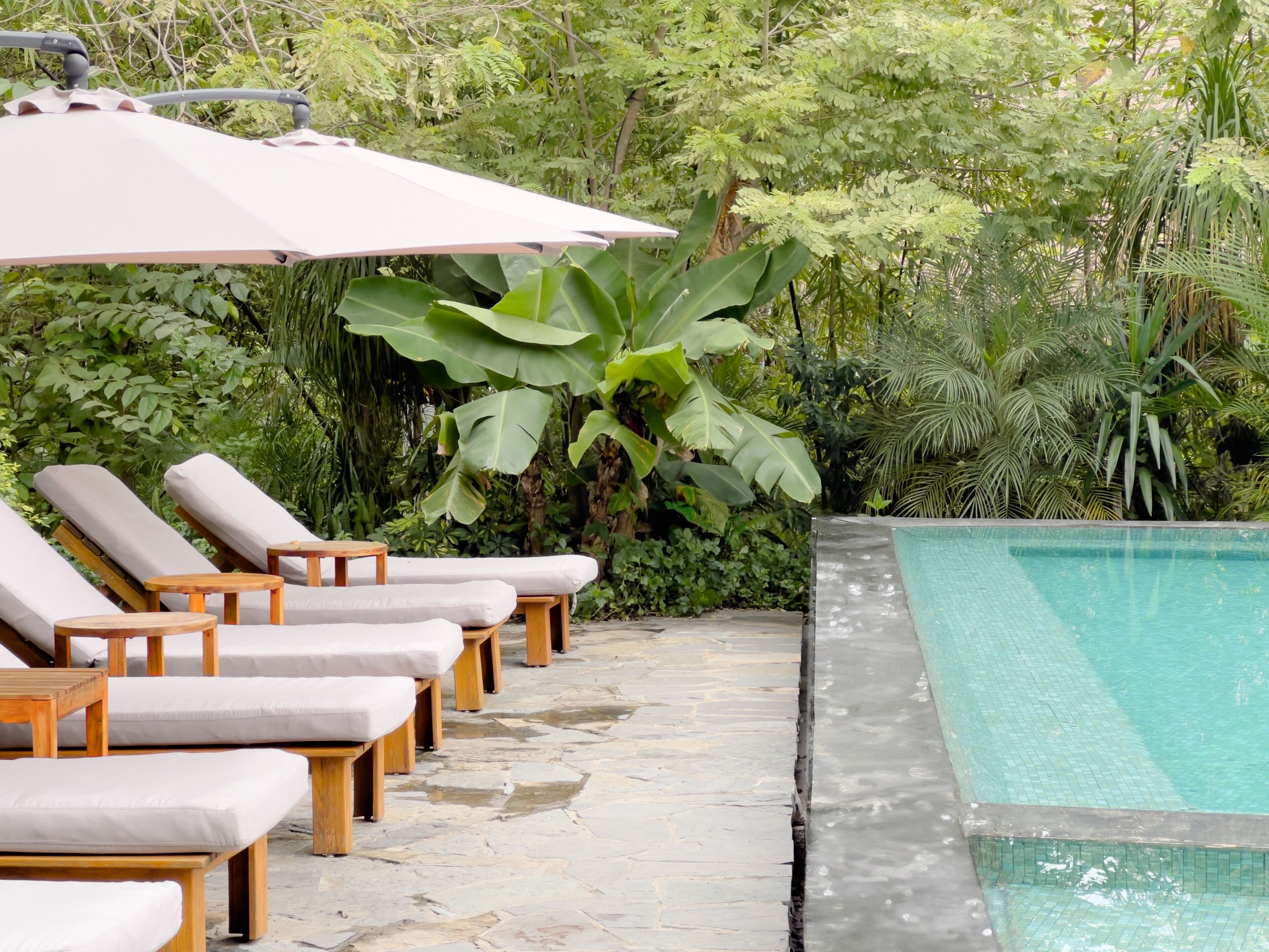 Un área junto a la piscina con sillones de descanso y una pérgola.