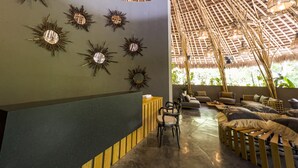 Una habitación con techo alto, diseño de techo de bambú y espejos tipo sol montados en la pared.