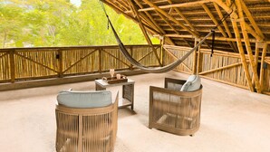Un espacio de estar al aire libre techado con muebles de bambú y una hamaca.