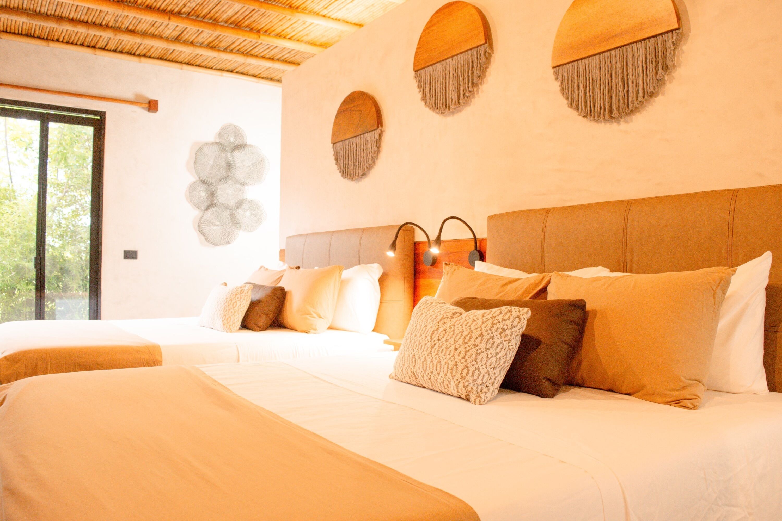 Un dormitorio con dos camas, un ventanal grande y un techo con diseño tejido.