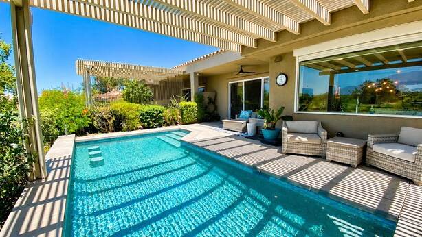 Piscina con toldo, mobiliario exterior y vista del paisaje circundante.