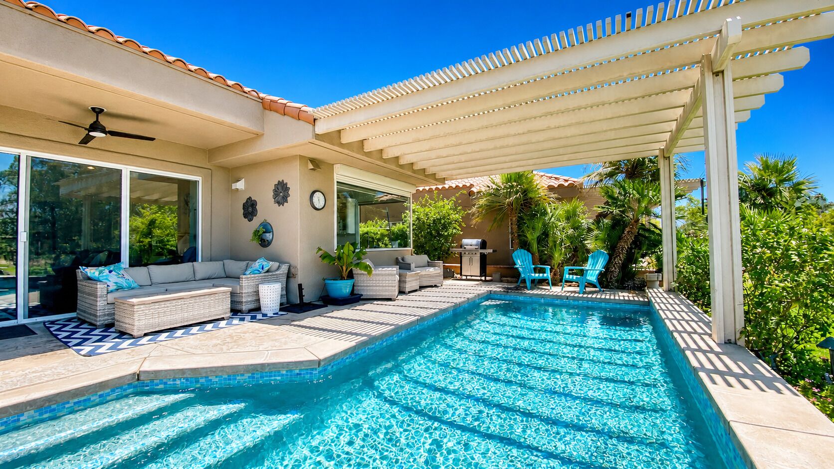 Une piscine agrémentée d’une pergola, d’un espace salon extérieur et d’un coin barbecue.