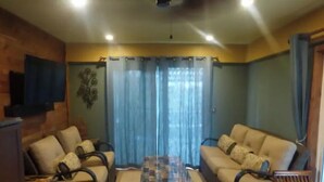 A living room with two sofas, a coffee table, and a television mounted on the wall. - May Rose Cottage lower level (Captain Cook)