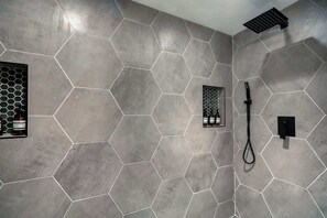 A bathroom with hexagonal tiles, a showerhead, and a handheld shower.