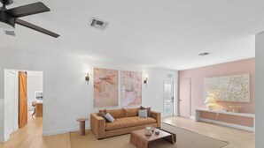 Un salon moderne avec un canapé marron, une table basse et deux tableaux abstraits accrochés au mur.