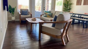 Una sala de estar con sofá, sillón, mesa de centro y un comedor con bancos.