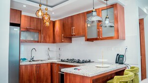 Una cocina moderna con armarios de madera, un refrigerador de acero inoxidable, una estufa a gas e iluminación colgante.