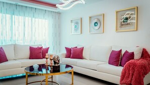 Una sala de estar moderna con un sofá blanco, una mesa de centro redonda y cojines decorativos.