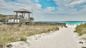 Une plage avec une promenade en bois menant à un kiosque.