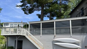Une propriété située au bord de l’eau, dotée d’un quai en bois, d’une terrasse couverte et d’un escalier menant à un porche grillagé.