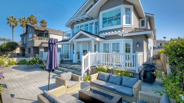 A modern two-story house with a balcony, outdoor seating area, and a fire pit. - Luxury Beachfront, Private Patio, Fire Pit, BBQ (Carlsbad)