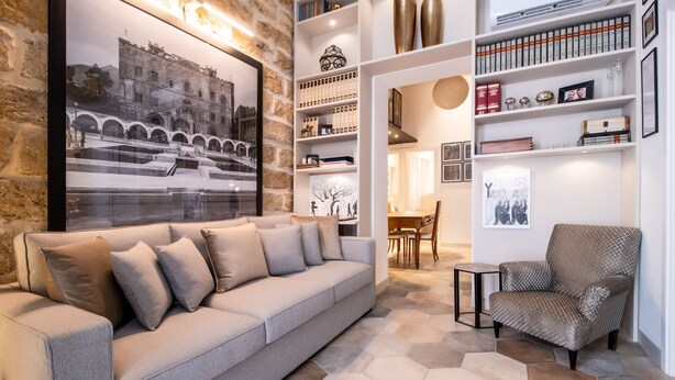 A modern living room with a grey sofa, patterned armchair, and a large framed photograph on the wall. - Zisa Suite - Design Apartment Just Steps from Palermo's Historic City Center (Palermo)