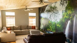 A living room with a sectional sofa, a dark leather couch, and a large mural of a waterfall. - Relaxing Rural Family Home with a great outdoor experience (Woodward)