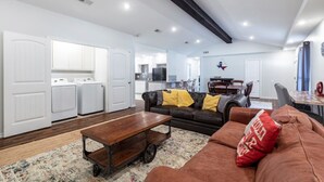 A spacious living area with a sofa, coffee table, and a kitchen in the background. - "Stadium Oasis" - A quick walk to the stadiums! (Arlington)