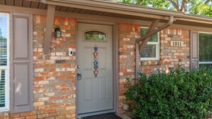 A brick house with a gray front door, a mailbox, and a number '1311' on the wall. - "Stadium Oasis" - A quick walk to the stadiums! (Arlington)