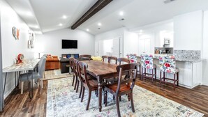 A spacious living area with a wooden dining table, comfortable seating, and a kitchen area with a countertop and appliances. - "Stadium Oasis" - A quick walk to the stadiums! (Arlington)