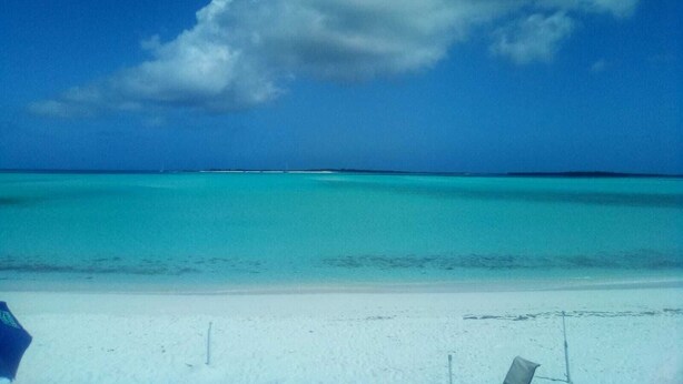 Une plage à l’eau turquoise et limpide, bordée d’un rivage sablonneux.