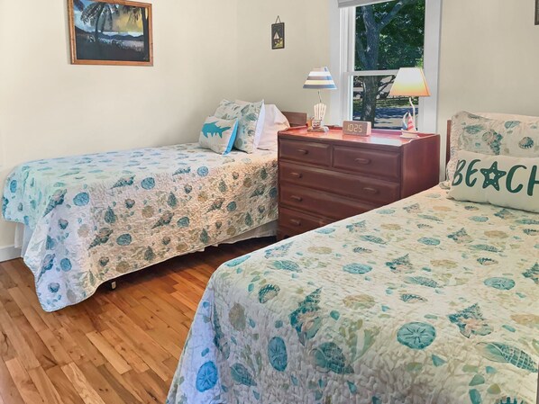 A bedroom with two beds, a dresser, a lamp, and a clock. - Quintessential Cape Cottage Near the Beach (South Yarmouth)