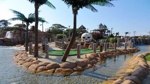 A water park with a large rock formation, palm trees, and a waterfall. - Quintessential Cape Cottage Near the Beach (South Yarmouth)