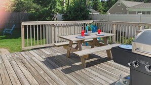 Une terrasse en bois avec une table de pique-nique, un barbecue et un espace salon extérieur.