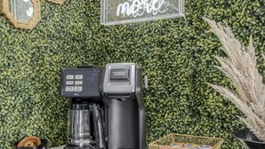 Un coin café équipé d’une machine à café, d’un panier de capsules de café et d’une pancarte sur laquelle est écrit : « Aimez votre amour encore plus. »