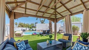 Un espace extérieur aménagé, abrité et doté d’une piscine, de chaises longues et d’une petite table agrémentée d’une plante.