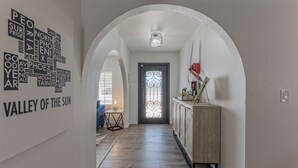 Un couloir doté d’un plafond en arc de cercle, d’un plancher en bois, d’une armoire avec une lampe rouge et d’une porte ornée d’un panneau de verre décoratif.