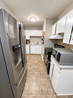 A compact kitchen with a refrigerator, microwave, stove, and sink.