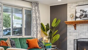 A modern living room with a green sofa, two armchairs, a coffee table, a fireplace, and a skylight. - Modern Huge Family Getaway | Fire Pit | 5BD/3BA (Arvada)
